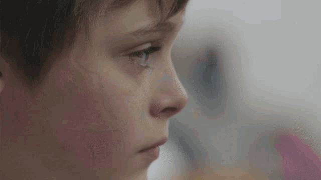 a close up of a young boy 's face with a tear running down his cheek