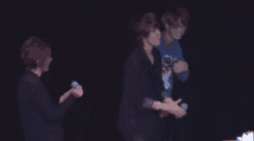 a couple of men standing next to each other holding hands .