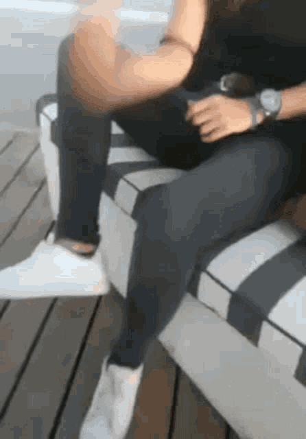 a woman wearing a watch is sitting on a bench