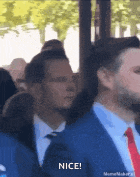 a man in a suit and tie says nice in a crowd of people