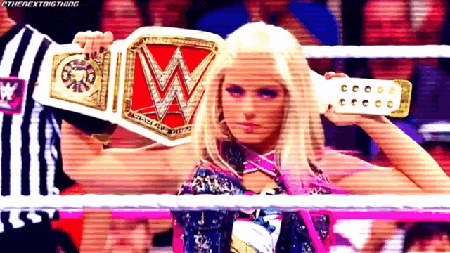 a woman in a wrestling ring is holding a wrestling championship belt .
