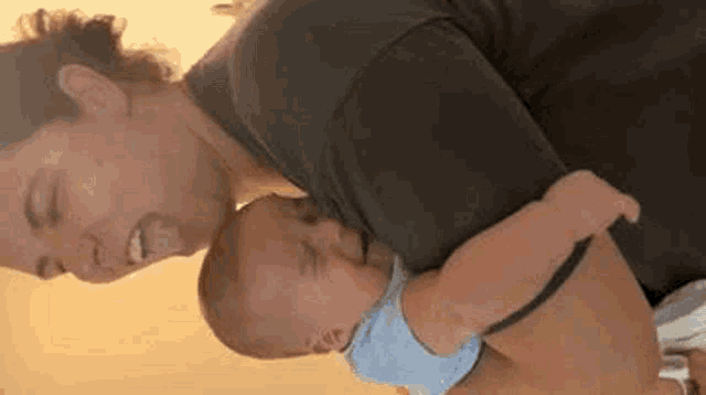 a woman is holding a crying baby in her arms and smiling .