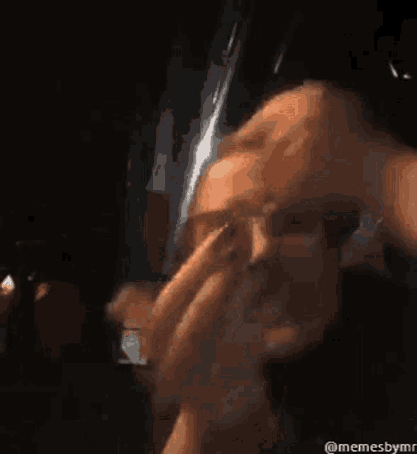a woman is covering her mouth with her hand while taking a selfie in a dark room .