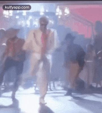 a man in a suit and tie is dancing on a dance floor in a club .