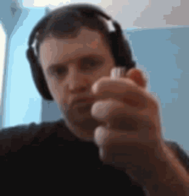 a man wearing headphones is holding a lighter in his hand and pointing at the camera .