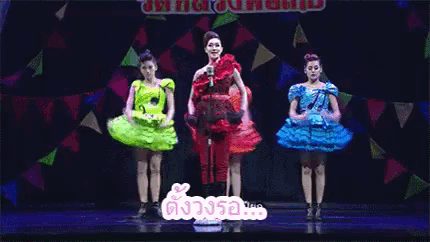 a group of women in colorful dresses are dancing on a stage with a sign that says ' a ' on it