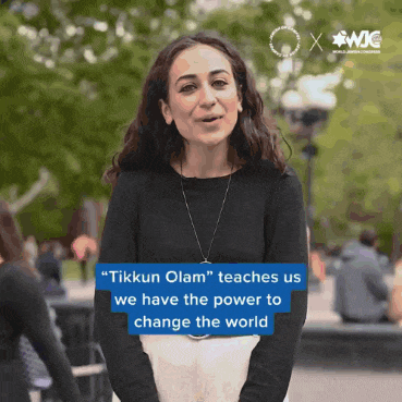 a woman stands in front of a sign that says tikkun olam