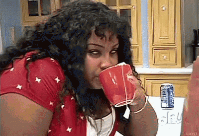 a woman in a red shirt is drinking from a red cup .