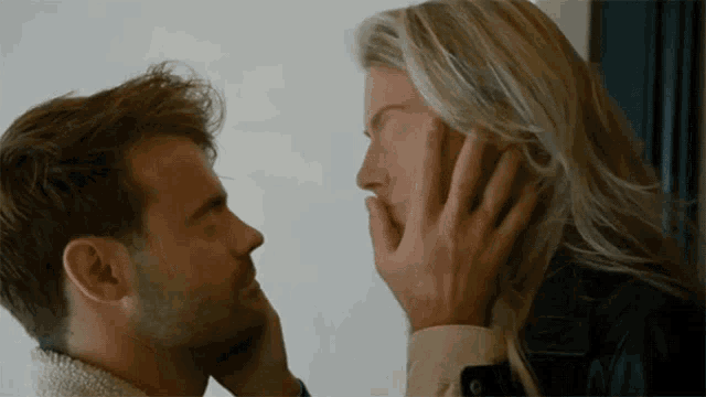 a man and woman are touching each other 's faces with their hands