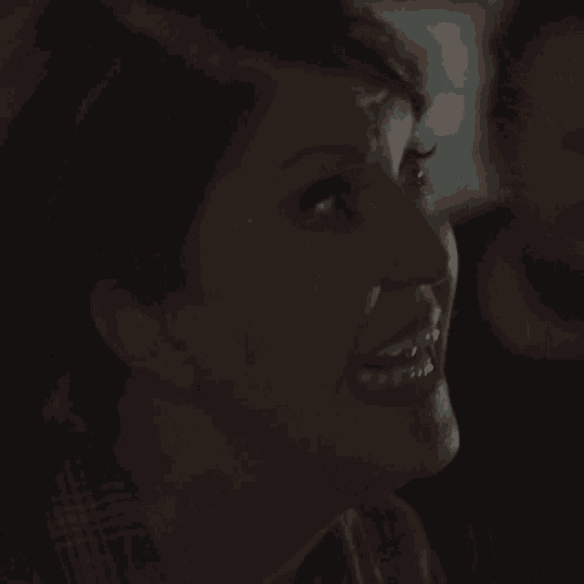 a close up of a woman 's face smiling in the dark