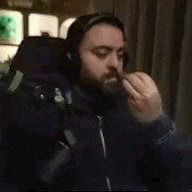 a man with a beard and headphones is sitting in front of a microphone in a room .