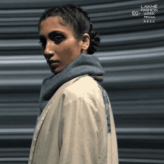 a woman is standing in front of a lakme fashion week ad