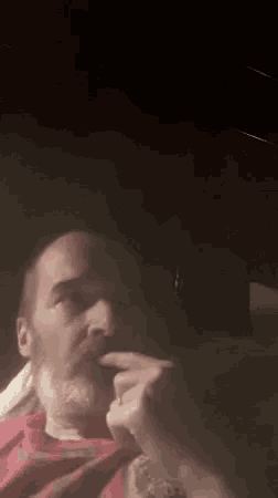 a man with a beard is smoking a cigarette while sitting in a car at night .