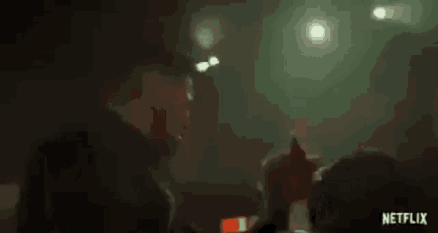 a man is holding another man 's hand in a dark room in a netflix trailer .