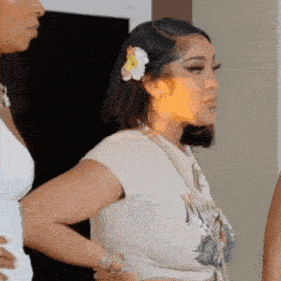a woman with a flower in her hair is standing next to another woman in a room .