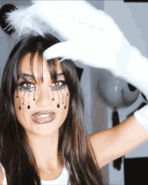 a woman with makeup on her face is wearing white gloves and a feather headband