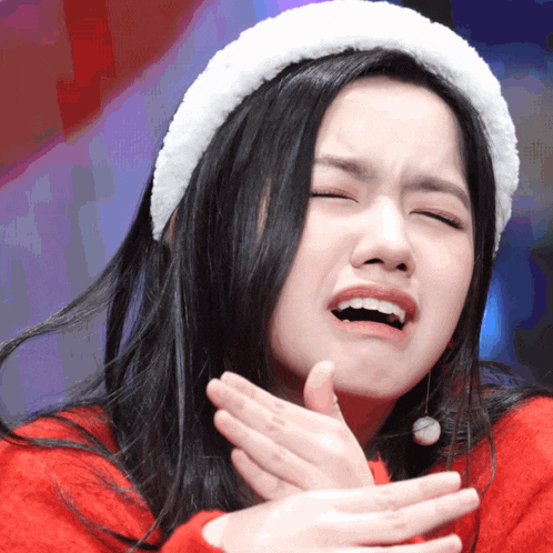 a woman wearing a santa hat and a red sweater making a funny face