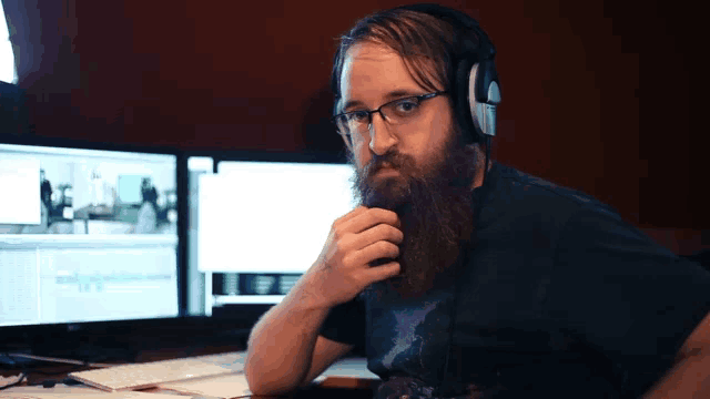 a man with a beard wearing headphones looks at the camera