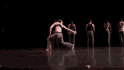 a group of dancers are performing on a stage in a dark room