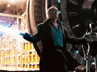 a man in a trench coat is holding a light while standing in front of a robot