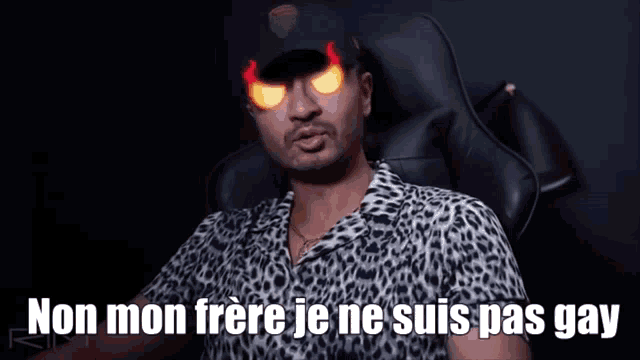 a man in a leopard print shirt is sitting in a chair with the words non mon frere je ne suis pas gay on the bottom