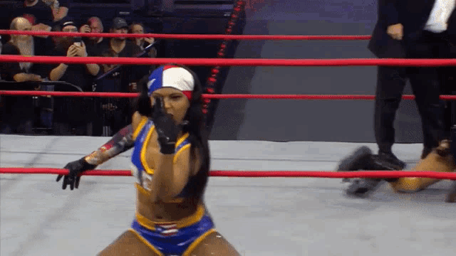 a woman in a blue and yellow outfit is kneeling in a ring