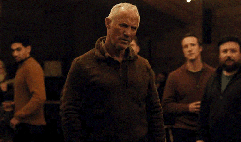 a group of men are dancing in a room with christmas lights in the background .