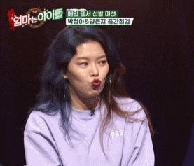 a woman with blue hair is wearing a purple sweatshirt and making a face