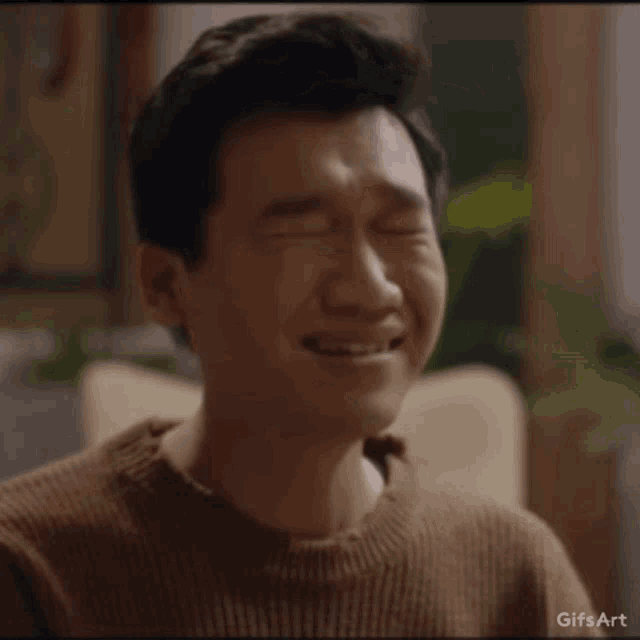 a man in a brown sweater is smiling and making a face .