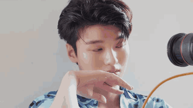 a young man covering his mouth with his hand while looking through a camera lens