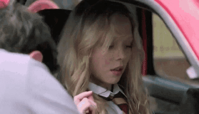 a woman in a school uniform is sitting in the back seat of a car with a man .