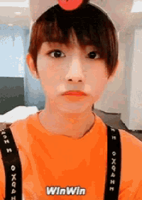a young boy wearing an orange shirt with the word win win on it