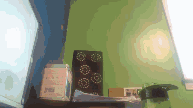 a bottle of water sits on a desk in front of a green wall with a picture of a man on it