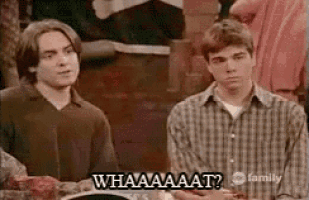 two men are sitting at a table with a plate of food and one of them is saying `` whaaaaat '' .