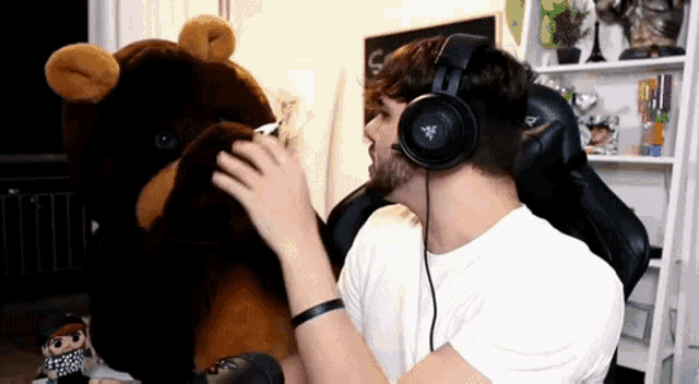 a man wearing headphones holds a stuffed bear