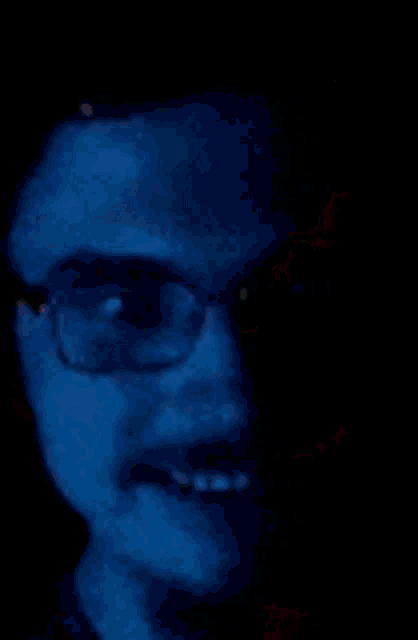 a close up of a man wearing glasses and a mustache in the dark .