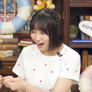 a woman wearing a white shirt with red hearts on it is holding hands with another woman in front of a bookshelf .