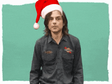 a man wearing a santa hat stands in front of a blue background