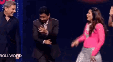 a man and a woman are dancing on a stage and the woman is wearing a pink sweater .