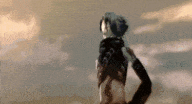 a person with a mask on their head is standing in front of a cloudy sky