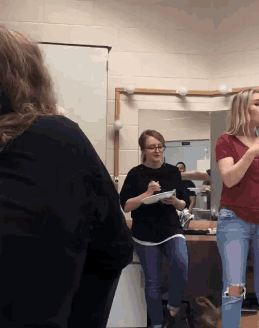 two women are standing in front of a mirror and one is holding a piece of paper