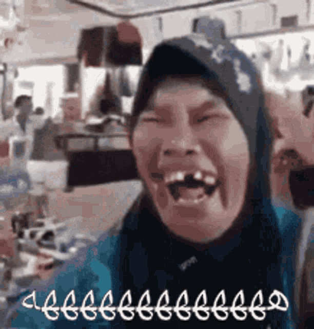 a woman wearing a hijab is laughing with her mouth open in a store .