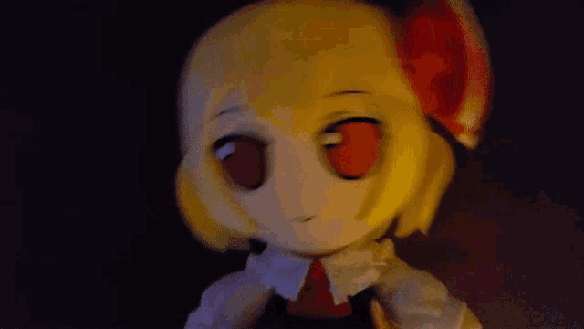 a close up of a stuffed doll with red eyes and yellow hair