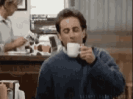 a man drinking a cup of coffee in a restaurant