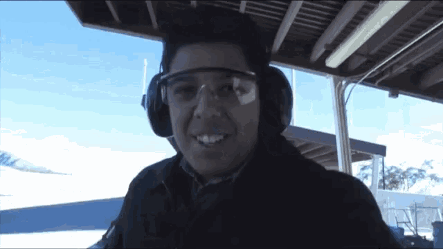 a man wearing headphones and goggles is smiling for the camera