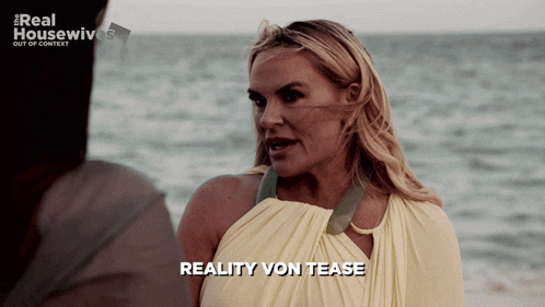a woman in a yellow dress is talking to a man in front of the ocean and the words reality von tease are on the screen