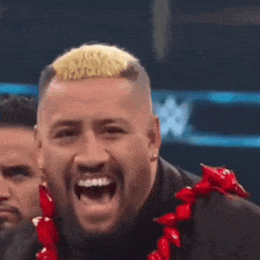 a man in a suit and a red lei is laughing .
