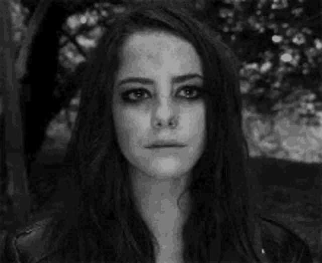 a black and white photo of a woman crying with a sad look on her face .