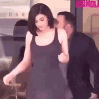 a woman in a black dress is walking with a man in a suit behind her .