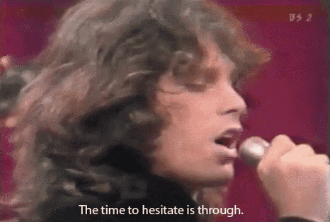a man is singing into a microphone with the words `` the time to hesitate is through '' written below him .